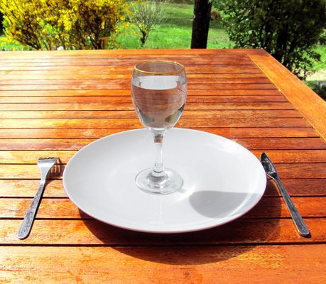 Empty plate with a glass of water set on a wooden table