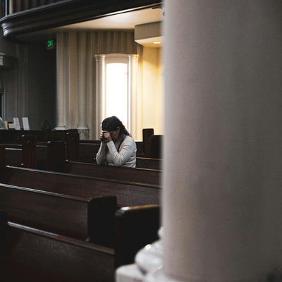 Church leader in reflective posture inside a parish sanctuary, representing repentance and leadership in mission.
